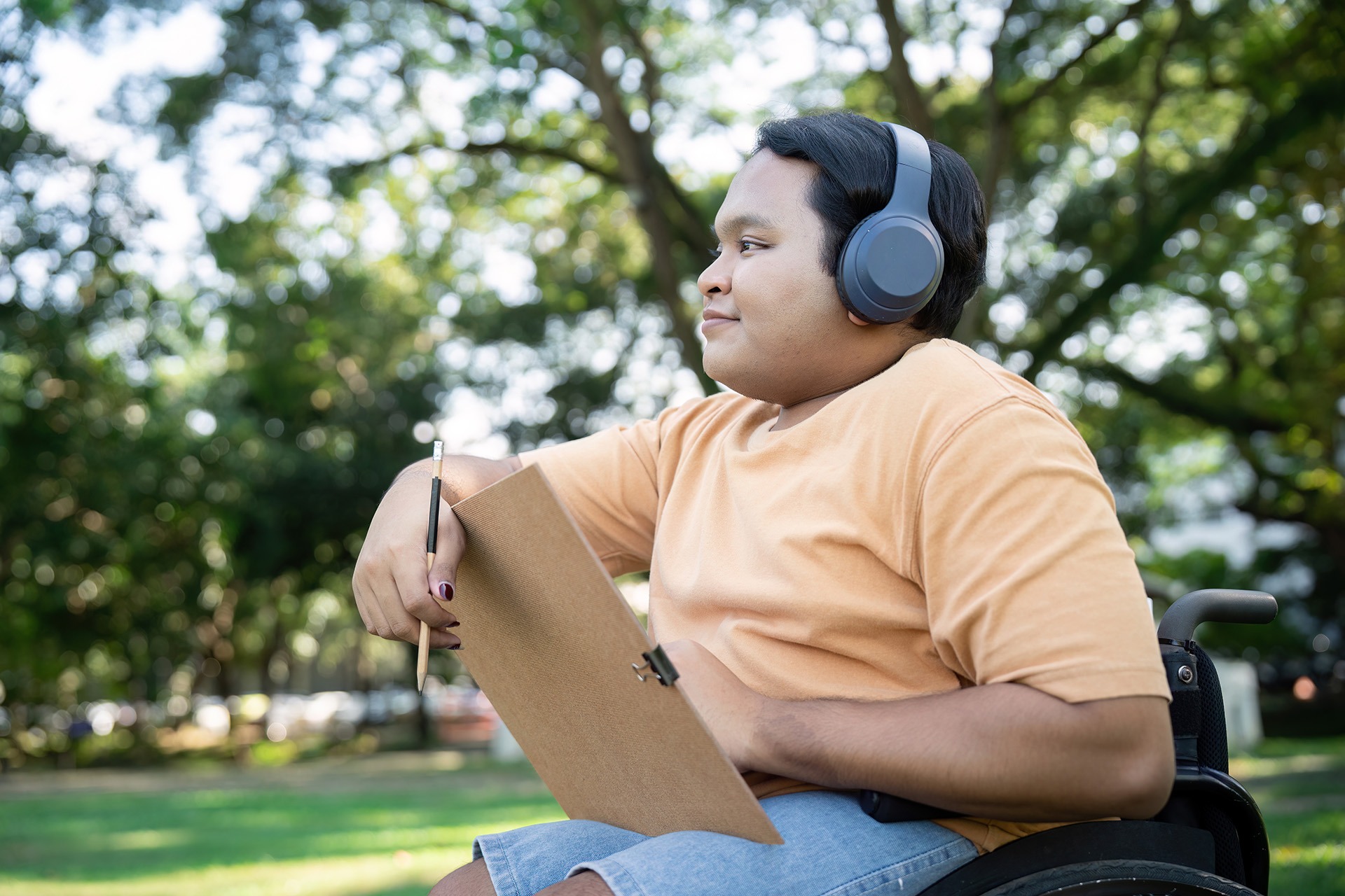 Person using a tablet outdoors while reviewing clothing design sketches for adaptive fashion development